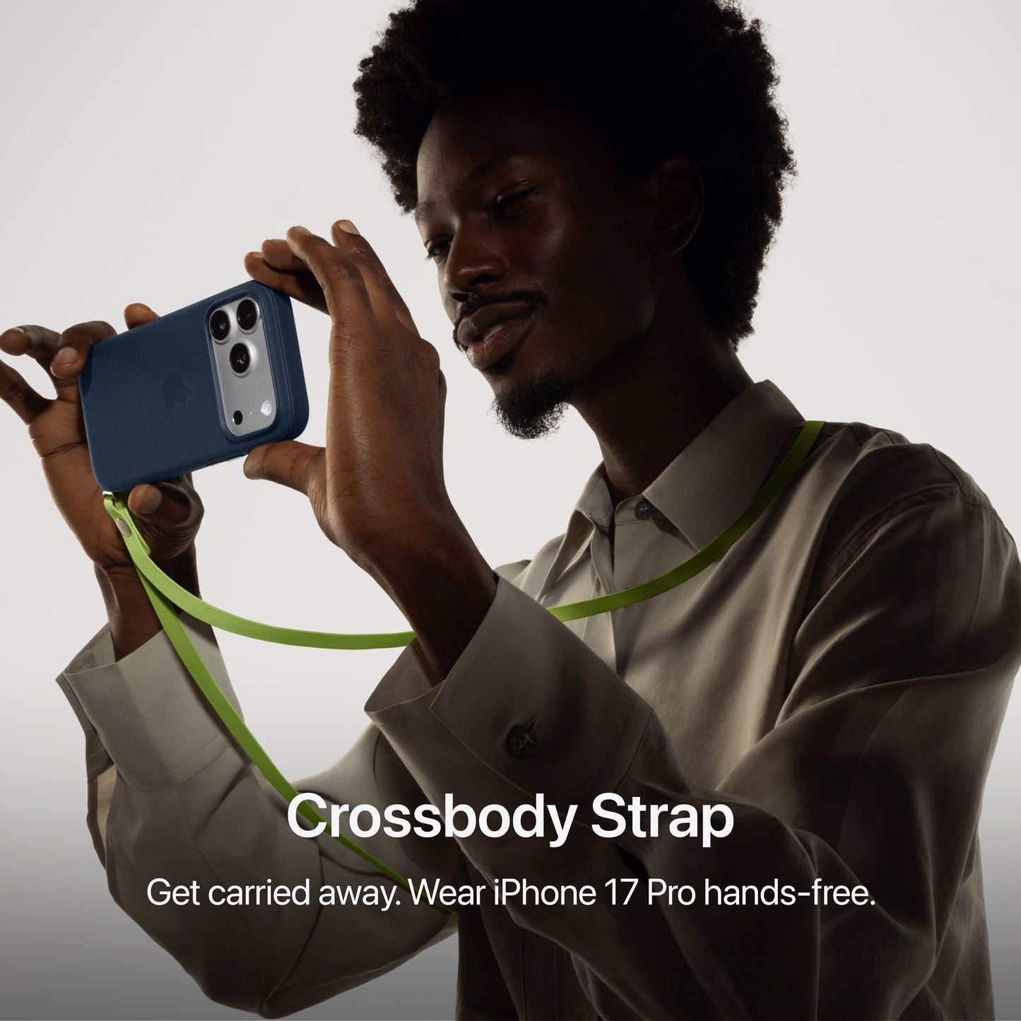Person using iPhone 17 Pro Max with crossbody strap accessory